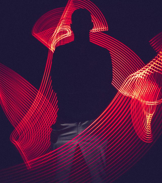 pexels-photo-3094799-3094799 A silhouette of a person surrounded by artistic red light trails, creating a dynamic visual effect.